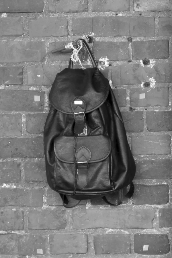 A leather backpack hanging on the wall